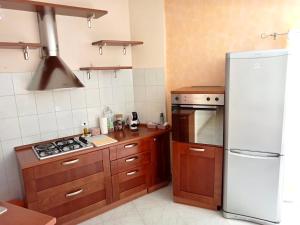 a kitchen with wooden cabinets and a white refrigerator at La mansarda dello scultore in Niscemi