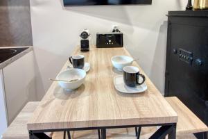 a wooden table with two bowls and mugs on it at Suite du lac, Centre-ville, Lac & Casino à 2 min in Enghien-les-Bains