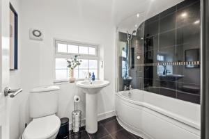 a bathroom with a toilet and a sink and a bath tub at Stunning Large Modern House - 3 Car Driveway - En-suite Master Bedroom - PS4 & Table Football in Leicester