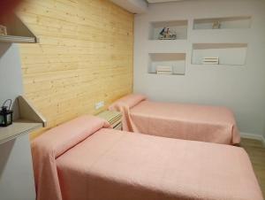 deux lits dans une chambre aux murs en bois dans l'établissement Alojamiento Rural La Tahona Gorafe, à Gorafe