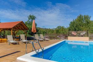 a swimming pool with chairs and an umbrella next to it at Villa Strikina kuca in Slivno