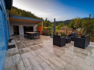 eine Terrasse mit Sofas, einem Tisch und Stühlen in der Unterkunft Chalet cosy avec sauna et spa dans le Massif des Vosges - FR-1-589-672 in Dommartin-lès-Remiremont