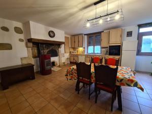 a kitchen with a table and chairs and a fireplace at Maison individuelle près de la Châtre, jardin privé, jacuzzi - FR-1-591-629 in La Berthenoux