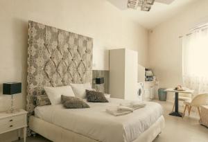 a white bedroom with a large bed with a headboard at Sliema Central Iprime Suites in Sliema