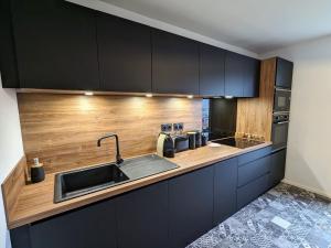 a kitchen with black cabinets and a sink at Appartement rénové avec jardin, parking et WiFi à Gérardmer - FR-1-589-678 in Gérardmer