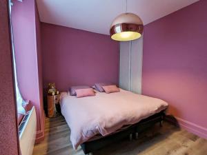 a bedroom with purple walls and a bed with pillows at Appartement rénové avec jardin, parking et WiFi à Gérardmer - FR-1-589-678 in Gérardmer +1 photo