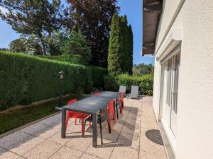 ein Holztisch mit roten Stühlen neben einem Gebäude in der Unterkunft Maison spacieuse avec jardin privé et WIFI, proche Épinal - FR-1-589-681 in Dinozé