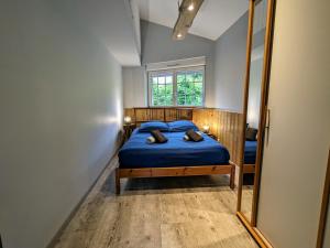 a bedroom with a blue bed and a mirror at Chalet de charme pour 6 pers., proche ski, WiFi, parking, animaux admis - FR-1-589-683 in Cornimont