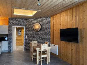 a dining room with a table and a television on a brick wall at Appartement moderne à La Bresse, 2 chambres, accès PMR - FR-1-589-687 in La Bresse