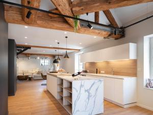 a kitchen with wooden ceilings and a living room at Loft moderne au charme ancien, climatisé, près de la Place Stanislas - FR-1-584-352 in Nancy