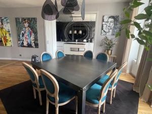 ein Esszimmer mit einem schwarzen Tisch und blauen Stühlen in der Unterkunft Appartement bourgeois et moderne au cœur d'Épinal, idéal pour découvrir la ville - FR-1-589-691 in Épinal + 27 Fotos