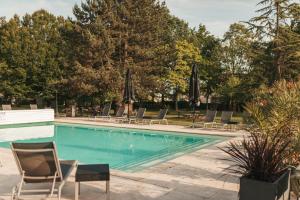 ein Schwimmbad mit Liegestühlen und Sonnenschirmen in der Unterkunft Le Dracy Hôtel et Spa in Dracy-le-Fort