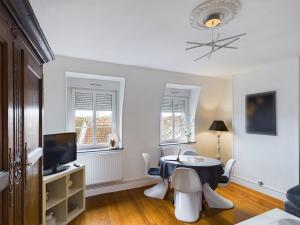 a living room with a table and chairs and a tv at Les Tanneurs in Metz
