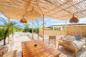 un patio con mesa, sillas y sombrilla de madera en Kokomo Villas by Aayan, en Canggu