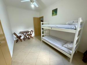 a room with two bunk beds and a table at Apartamento aconchegante no Centro de Peruibe in Peruíbe