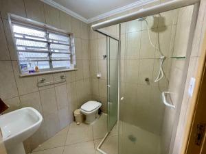 a bathroom with a shower and a toilet and a sink at Apartamento aconchegante no Centro de Peruibe in Peruíbe +13 photos