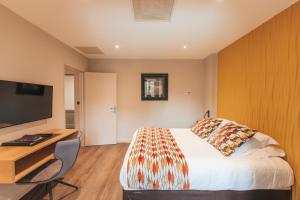 ein Schlafzimmer mit Bett, Schreibtisch und Fernseher in der Unterkunft Le Dracy Hôtel et Spa in Dracy-le-Fort