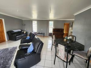 a living room with black leather furniture and a table at The O'Bryan Cottage in Burra