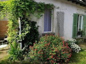 a house with a bunch of flowers in the yard at Chambre dans une dépendance La Rosette in Fontenay-sous-Bois +1 photo
