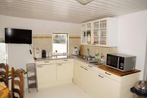 Una cocina con gabinetes blancos y un microondas. en The Island Houseboat, en Ámsterdam