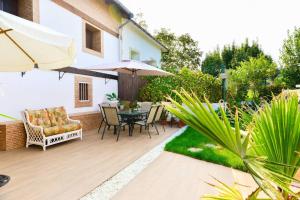 a patio with a table and chairs and an umbrella at Rural Enjoy Cantabria in Arnuero