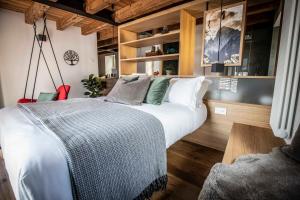 a bedroom with a large white bed and wooden floors at BOTTONERA casa vacanza in Chiavenna