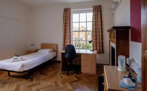 a bedroom with a bed and a desk and a window at Sidney Sussex College, Cambridge in Cambridge