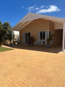 a brick house with two chairs on a patio at Blue Holes Bungalow in Kalbarri