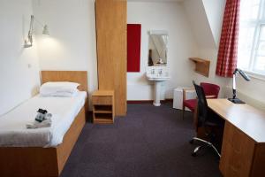 a hotel room with a bed and a desk and a sink at Sidney Sussex College, Cambridge in Cambridge