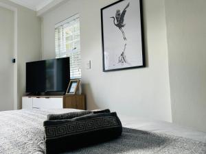 a bedroom with a bed and a flat screen tv at Charming Flatlet Near the Amazing Sunset Beach in Cape Town +12 photos