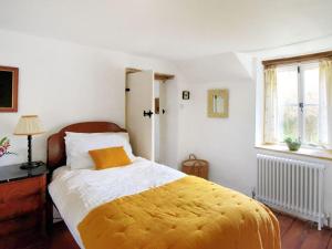 a bedroom with a bed with a yellow blanket at Church Cottage in Bridport
