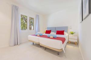 a white bedroom with a large bed with red pillows at Cielo de Bonaire in Alcudia +66 photos