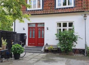 a red door on a white house with a bench at Well Design apartment in Rønne in Rønne +2 photos