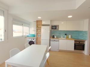a kitchen with a white table and white cabinets at Play-Puig Beach Flat in El Puig