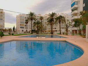 a large swimming pool with palm trees and buildings at Play-Puig Beach Flat in El Puig