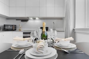 a dining table with a bottle of champagne and glasses at Stylish Retreats on Olympic Way in London