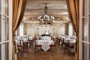 a dining room with tables and chairs and a chandelier at Grand Hotel Kronenhof in Pontresina