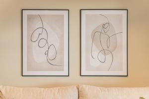 two framed art prints on a wall above a couch at PRESTIGE ZEN Apartment & SPA by Posesja Apartamenty in Grzybowo