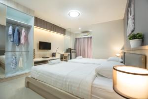 a hotel room with two beds and a tv at Central Place Serviced Apartment Angsila in Ang Sila
