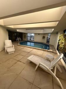 a swimming pool with two chairs and avisor at Hotel Biena Sena Madureira PqIbirapuera Com Garagem 907 in Sao Paulo