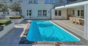 a swimming pool in front of a house at Charming Flatlet Near the Amazing Sunset Beach in Cape Town