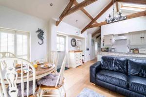 a living room with a black leather couch and a table at Lower Trowan Cottage in Sharnbrook