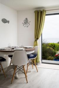 Un comedor con mesa y sillas y una ventana. en Seasky, en Praa Sands
