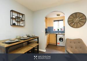 a kitchen with a table and a clock on the wall at Telford 2-Bedroom Apartment in Telford
