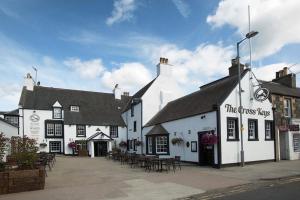 um edifício branco com mesas e cadeiras numa rua em The Cross Keys em Peebles