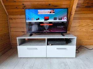 a tv on a white entertainment center with a flat screen at Petit chalet avec terrasse in Oust