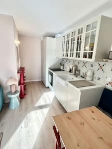 a kitchen with white cabinets and a wooden floor at Magnifique logement plein centre face aux pistes in Auron +13 photos