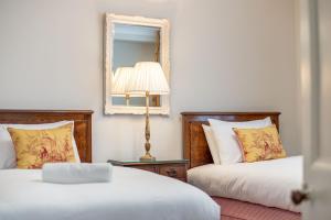 a bedroom with two beds and a mirror and a lamp at The Windmill Room - 1 min to Old Course in St. Andrews
