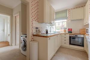 a kitchen with white cabinets and a washer and dryer at The Windmill Room - 1 min to Old Course in St. Andrews