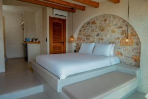 a bedroom with a white bed and a stone wall at Churchill Townhouse in Bodrum City